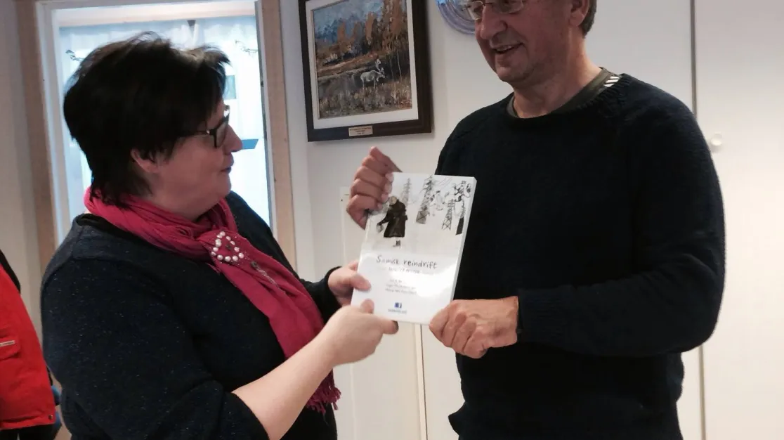 Bilde av to personer som holder en ny bok om reindrift.