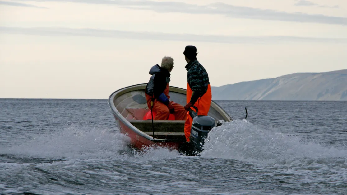 To personer i liten båt i en fjord.
