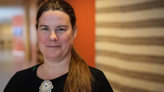 Smilende kvinne med svart genser og sølje.