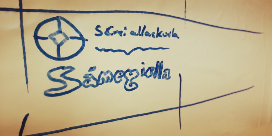 Govva whiteboard tavvalis mas sárgojuvvon Sámi allaskuvla namma, logo ja sátni Sámegiella.