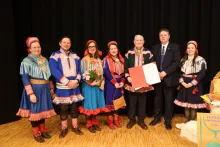 Bildet viser en gruppe på sju personer som står på en scene med svart bakgrunn og tregulv.