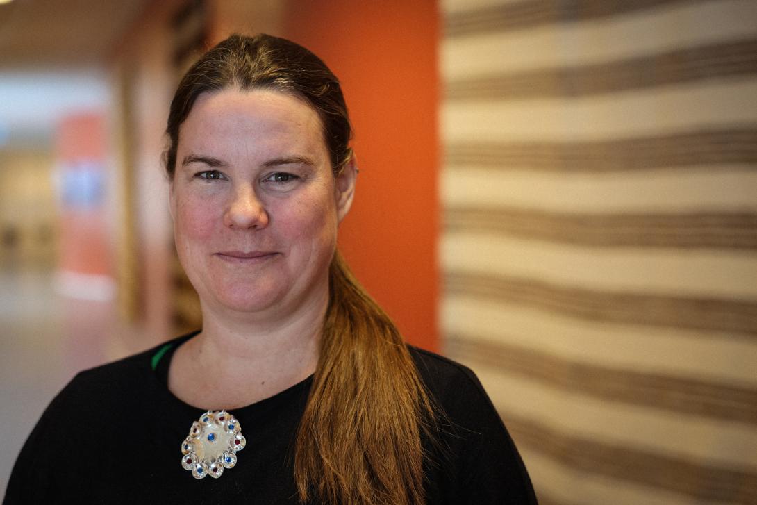 Smilende kvinne med svart genser og sølje.
